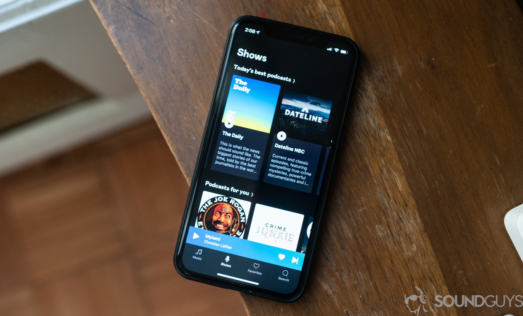 Deezer app podcasts section on iPhone Shot of podcasts section of iOS Deezer app on iPhone 11 Pro on wooden table.