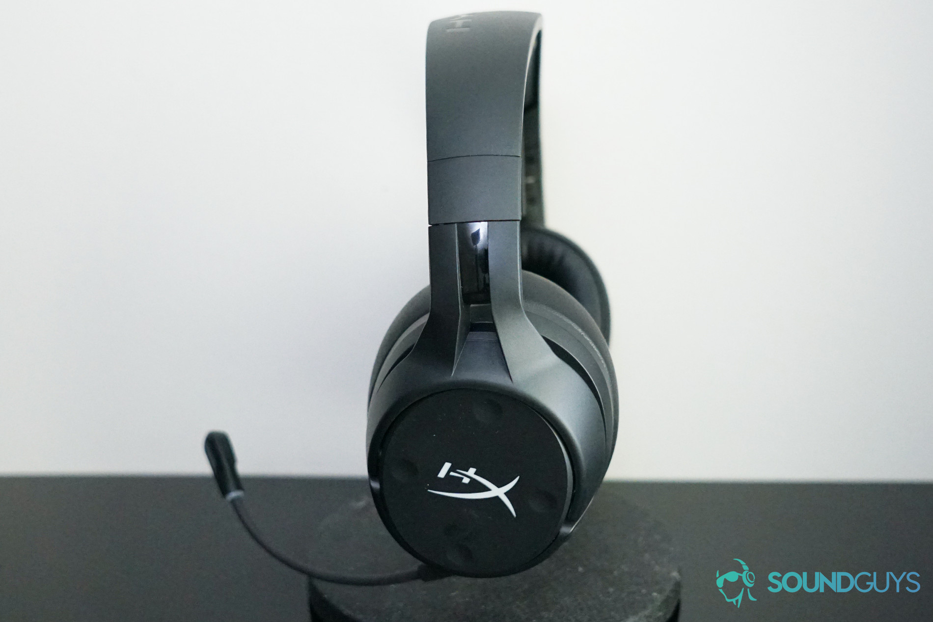The HyperX Cloud Flight S sits on a stand on a black reflective surface,