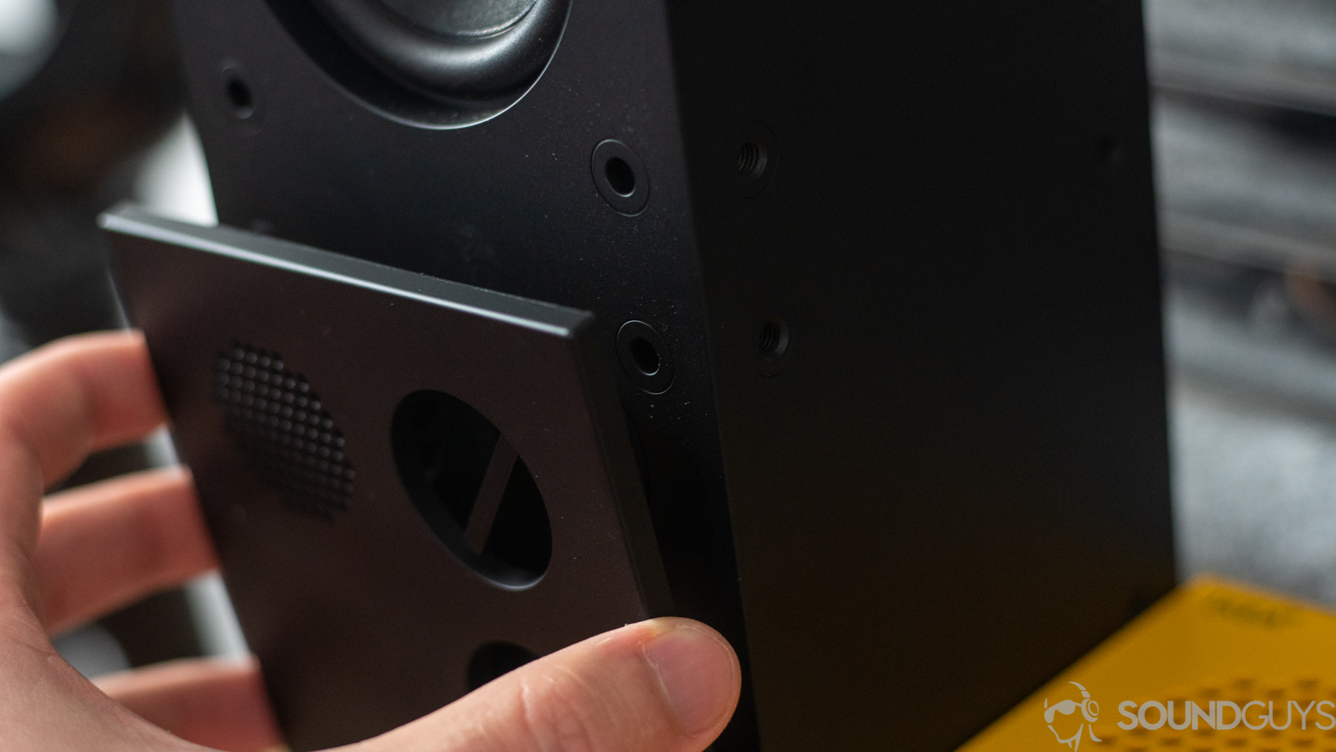 Close-up of man taking off the removable front grille of the Frekvens speaker.