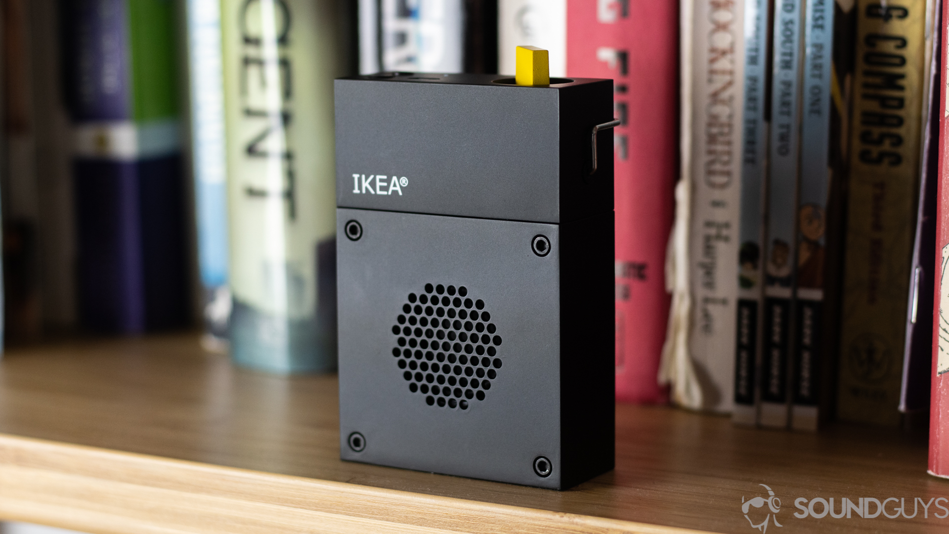 Pictured is the Frekvens Portable speaker on a shelf in front of books.