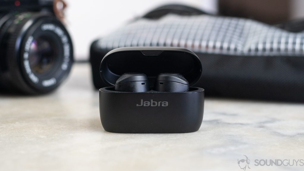 The Jabra Elite 75t pictured on a marble table with a camera and bag in the background.
