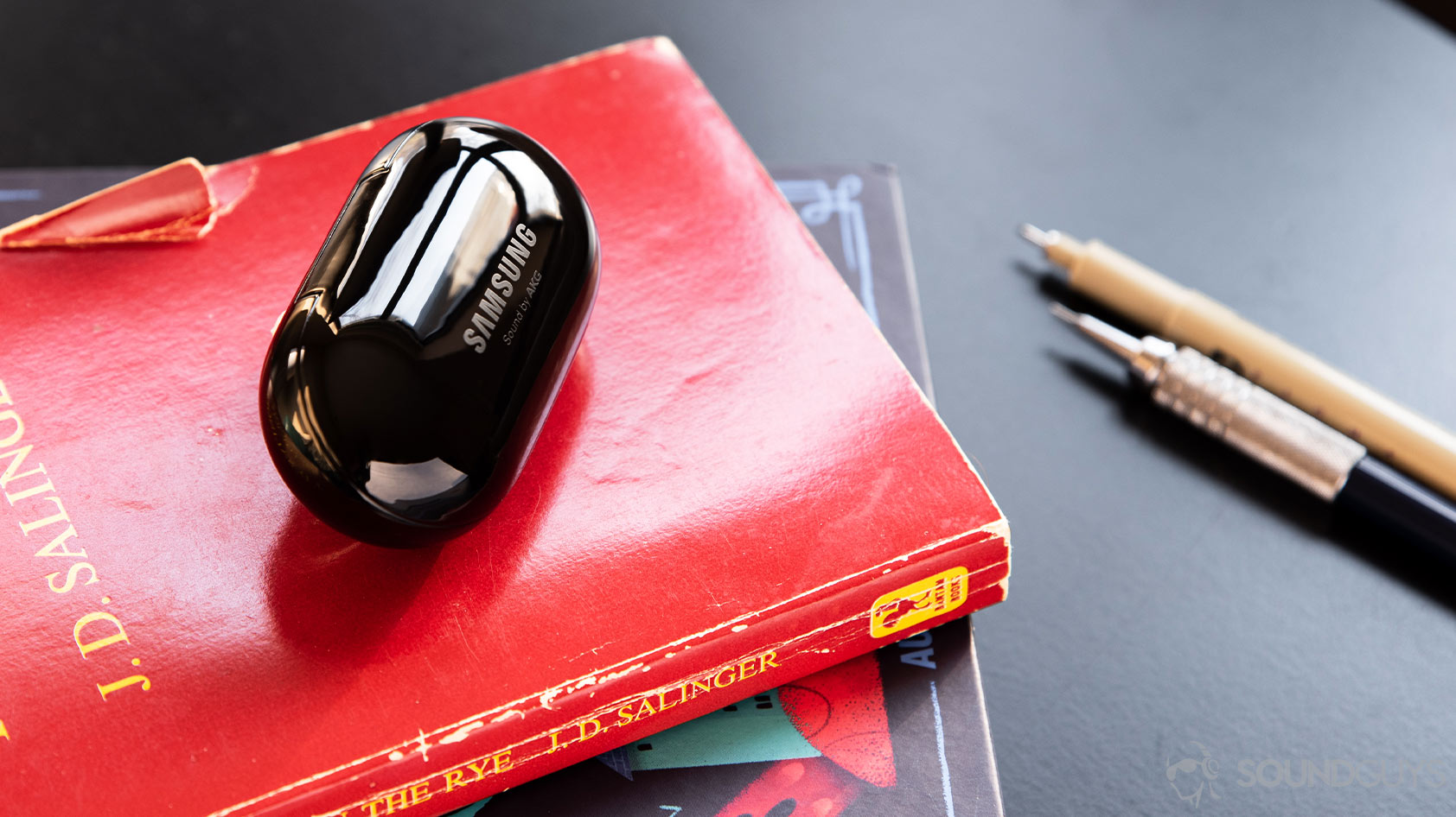 A picture of the Samsung Galaxy Buds Plus case in black on top of books.