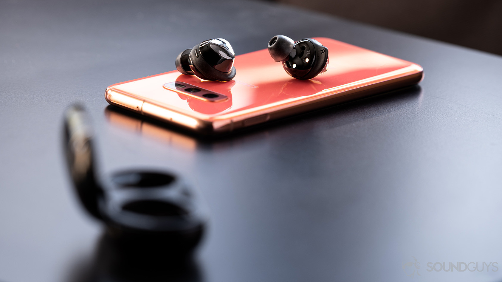 A picture of the Samsung Galaxy Buds Plus earbuds on top of the Galaxy S10e smartphone in flamingo pink.