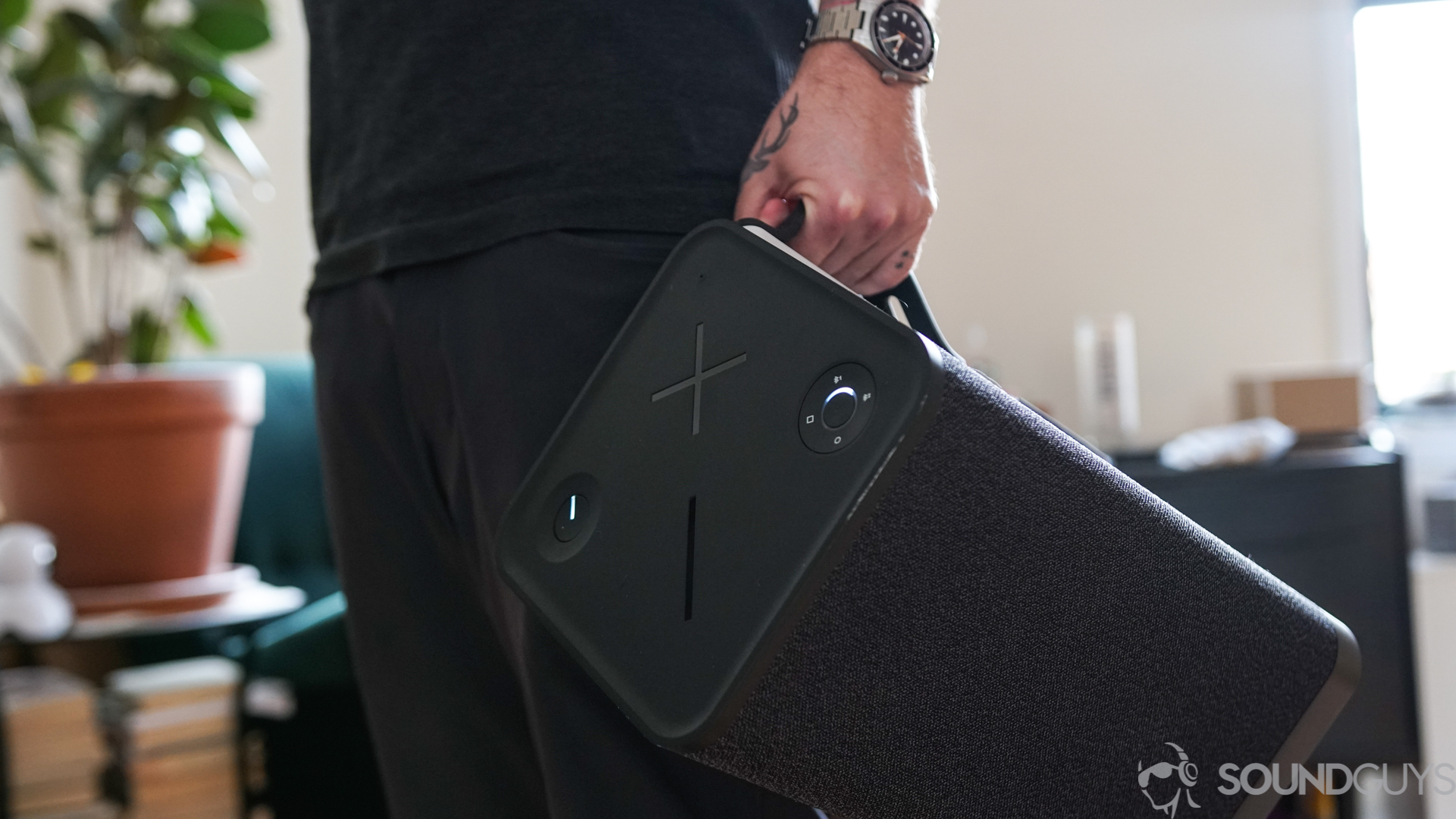 A man holds the UE Hyperboom Bluetooth speaker via the handle.