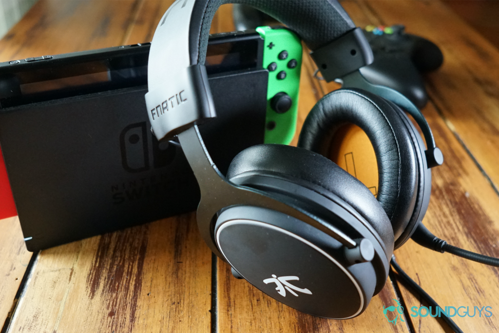 The fnatic react headset sits on a wooden table, leaning on a docked Nintendo Switch, in front of an Xbox One question