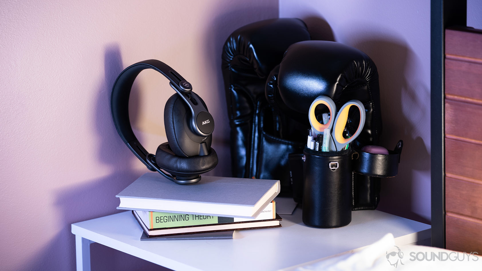 A picture of the AKG K371 wired over-ear headphones on a nightstand in front of boxing gloves.
