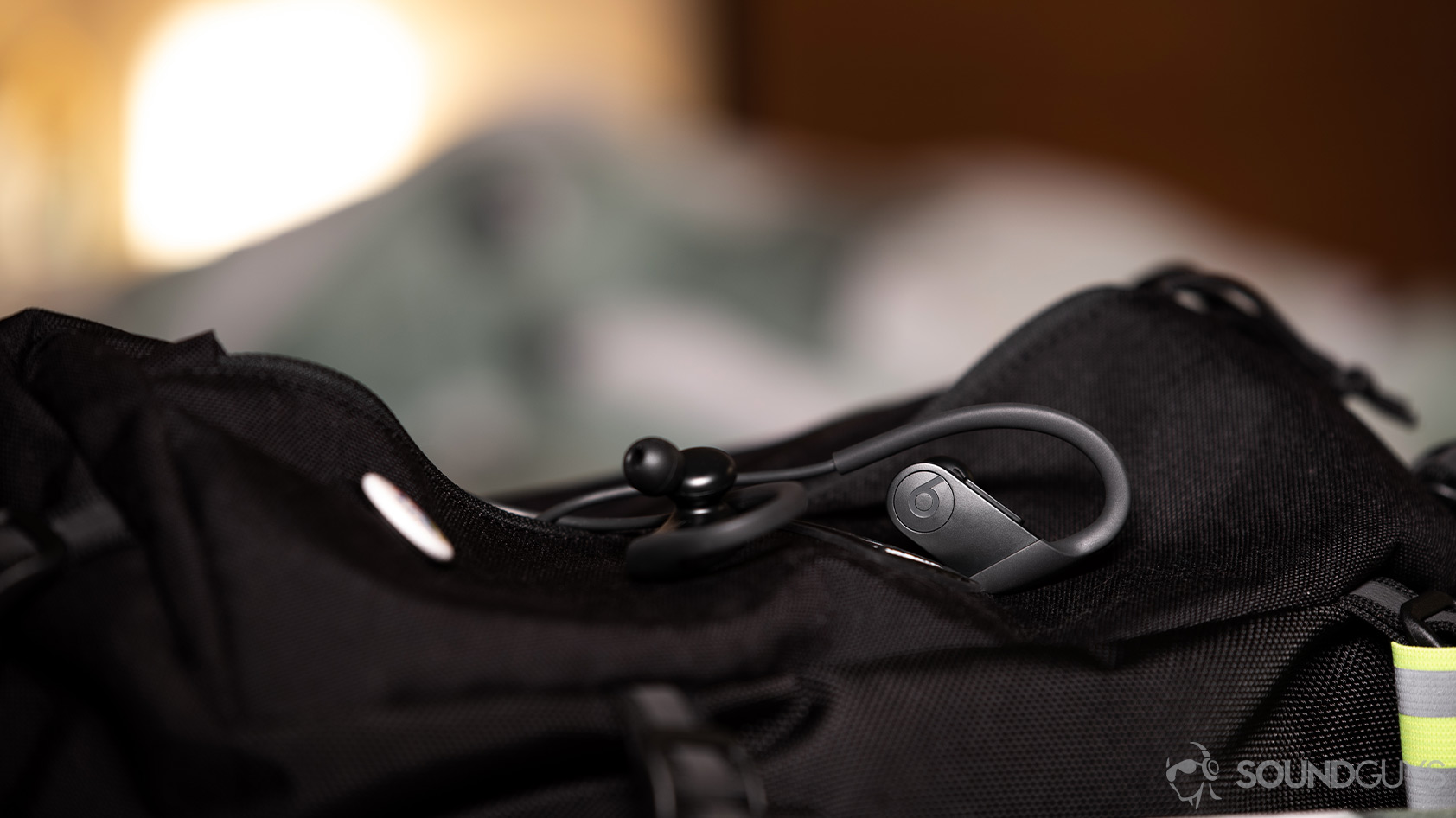 A picture of the Apple Beats Powerbeats workout earbuds on top of a nylon sling bag.