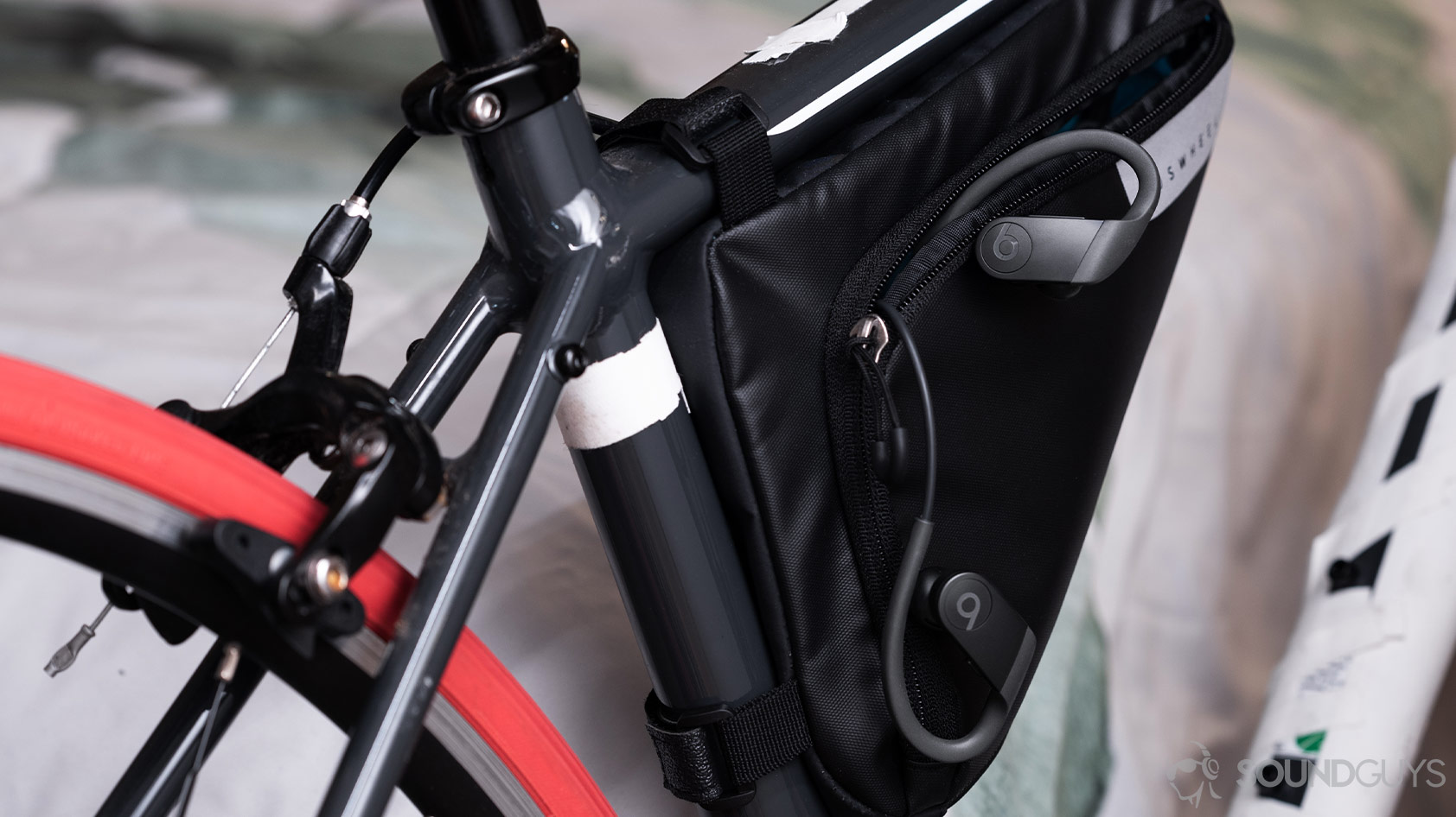 The Apple Beats Powerbeats workout earbuds emerging from a cycling carrying pouch attached to a road bike.