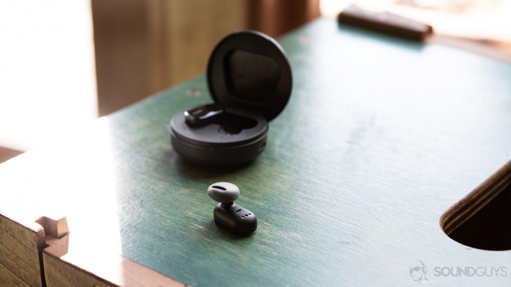 A photo of the LG Tone Free HBS FL7 true wireless earbuds nozzle-up on a wood surface.