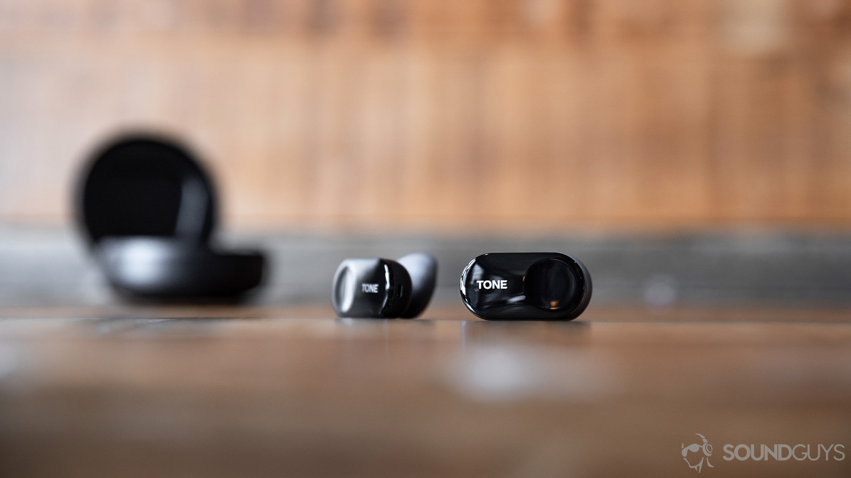 LG Tone Free HBS FL7-true wireless earbuds A photo of the LG Tone Free HBS FL7 true wireless earbuds outside of the charging case on a wood surface.