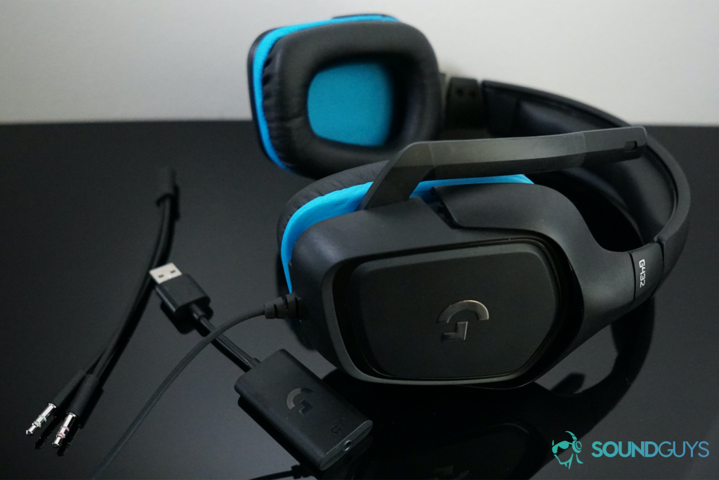 The Logitech G432 lays on a black surface next to its 3.5mm adapter.