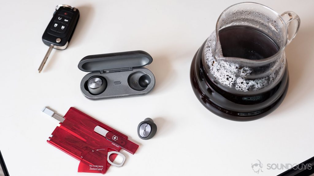 A photo of the Sol Republic Amps Air Plus true wireless noise canceling earbuds on a coffee table with car keys and a multifunction card on it.