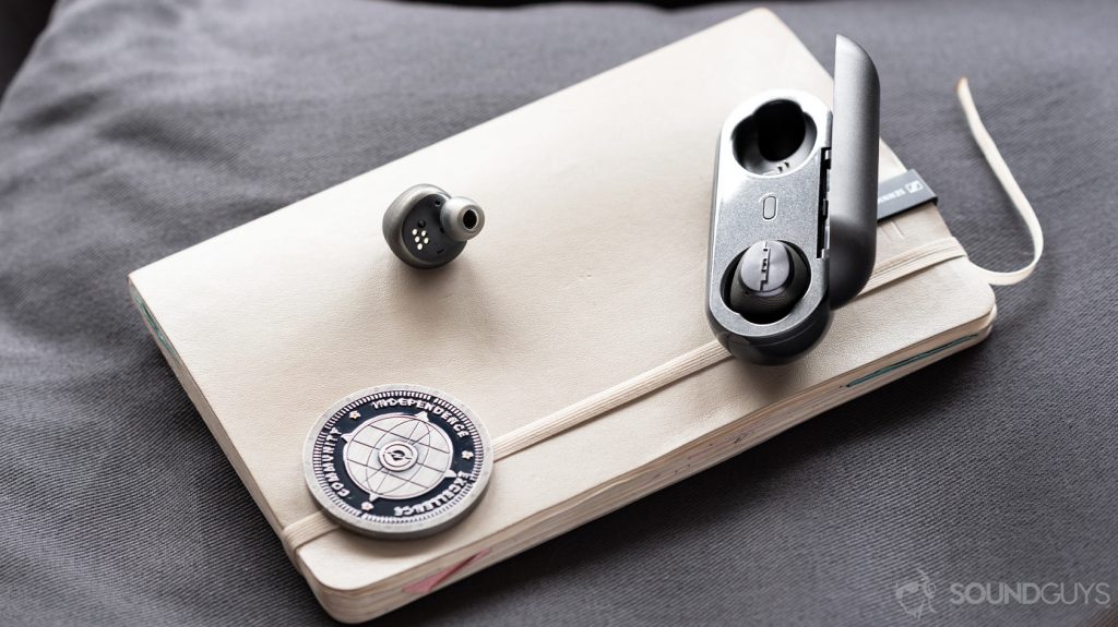 A photo of the Sol Republic Amps Air Plus true wireless noise canceling earbuds with one in and one out of the open charging case.