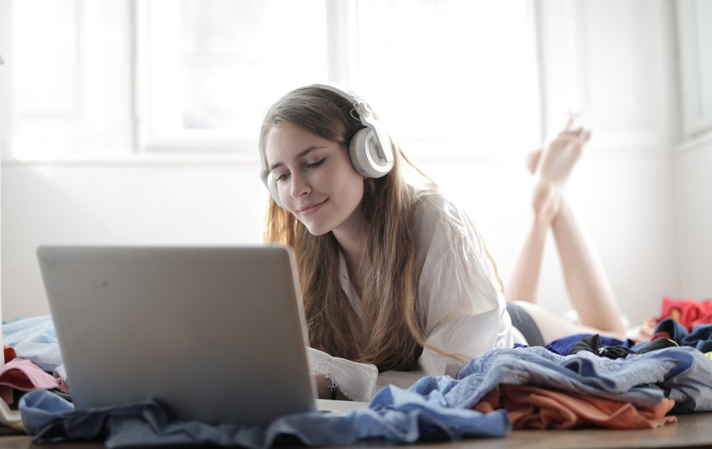 A photo of a woman listening to music on the internet, a common strategy in how to find new music.