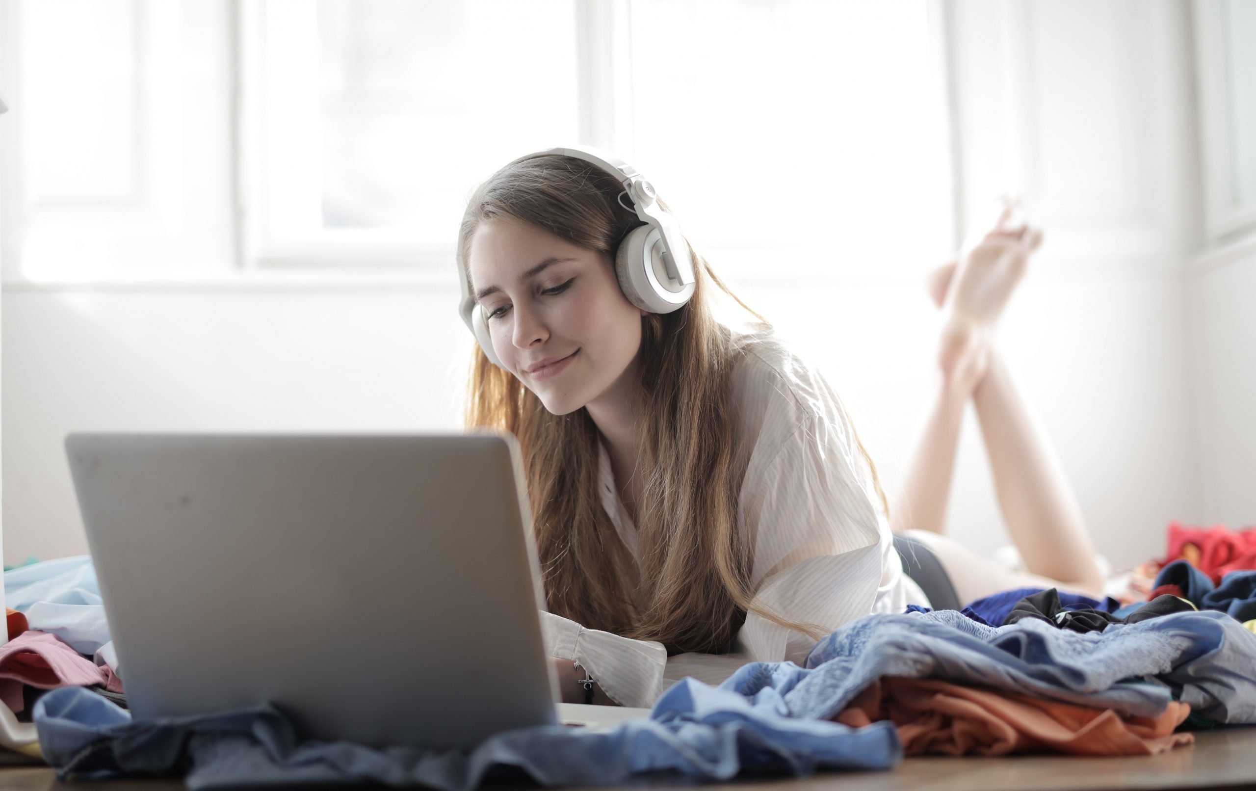 A photo of a woman listening to music on the internet, a common strategy in how to find new music.