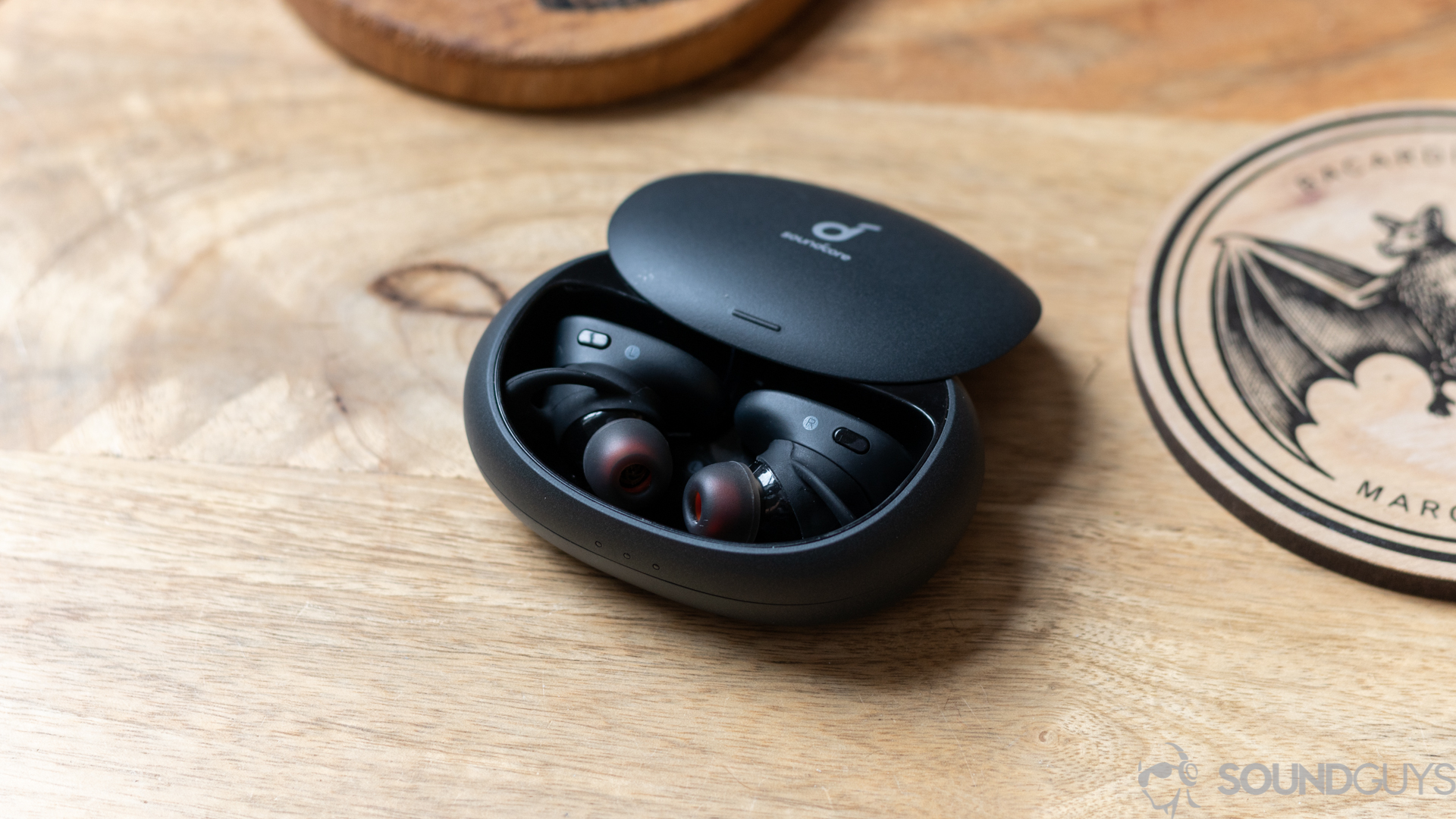 Anker Soundcore Liberty 2 Pro earbuds in the charging case with the lid open while resting on a wooden suface