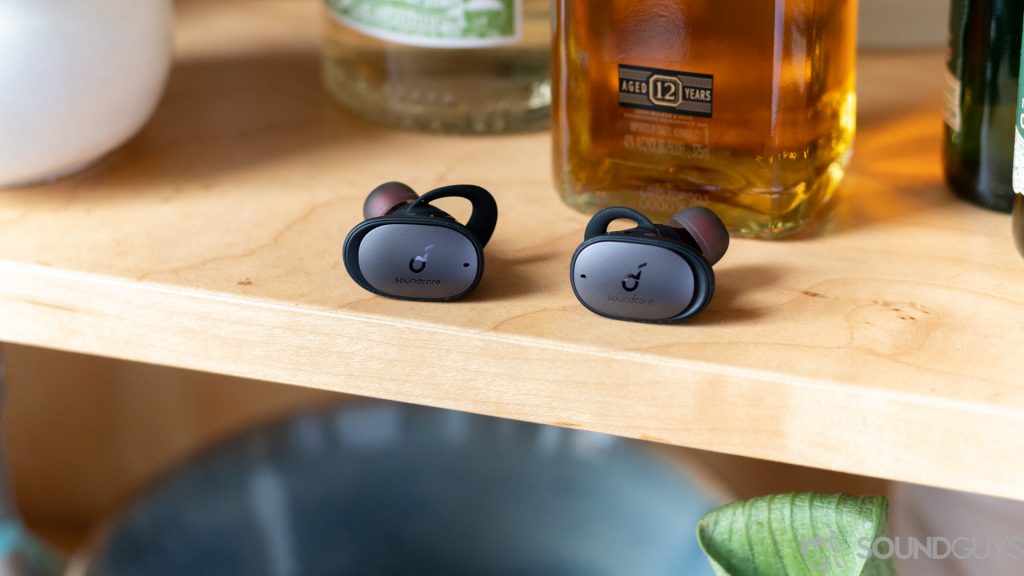 Anker Soundcore Liberty 2 Pro earbuds on shelf in front of liquor bottle.