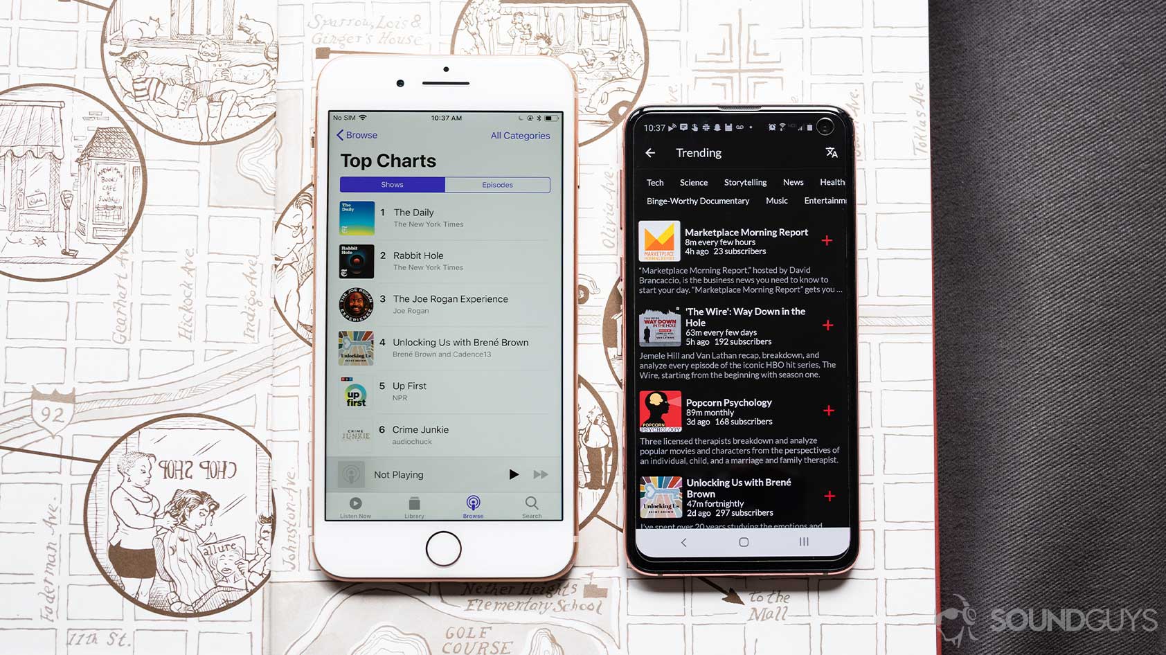 Apple Podcasts open on an iPhone 8 Plus next to the PlayFM app open on a Samsung Galaxy S10e on top of an open book.