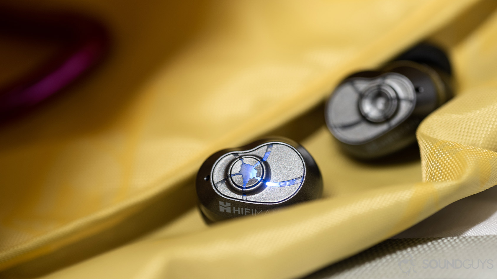 A close-up photo of the HiFiMan TWS600 true wireless earbuds on a yellow nylon surface.
