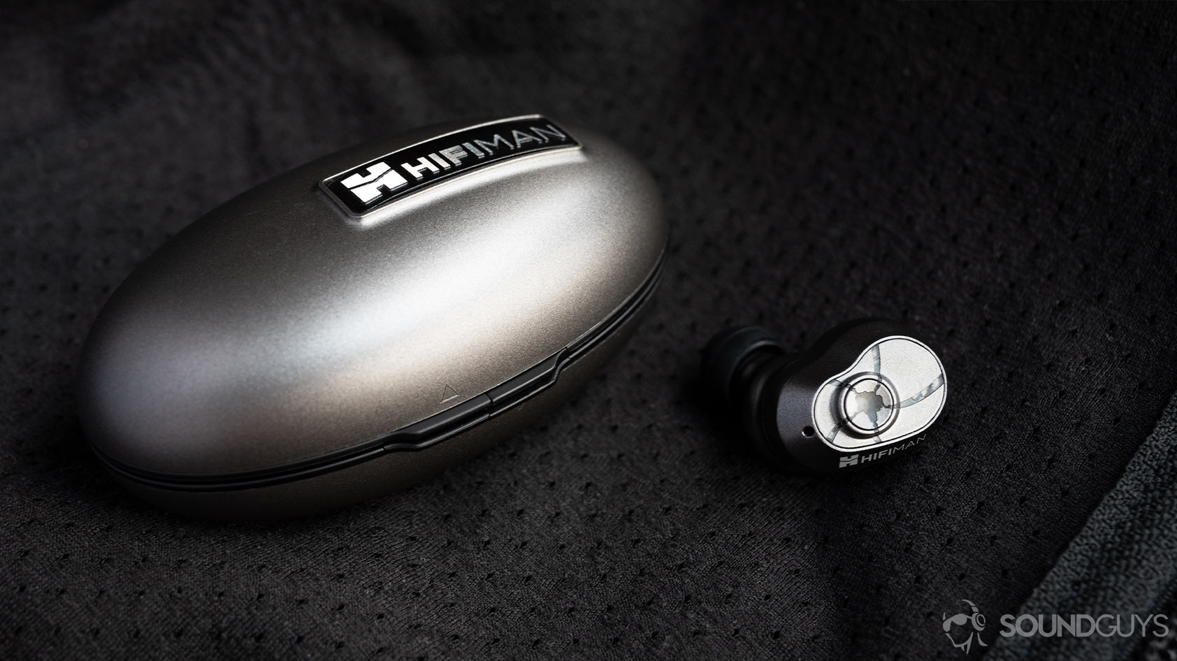 A photo of the HiFiMan TWS600 true wireless earbuds closed charging case with one earbud out of the case.