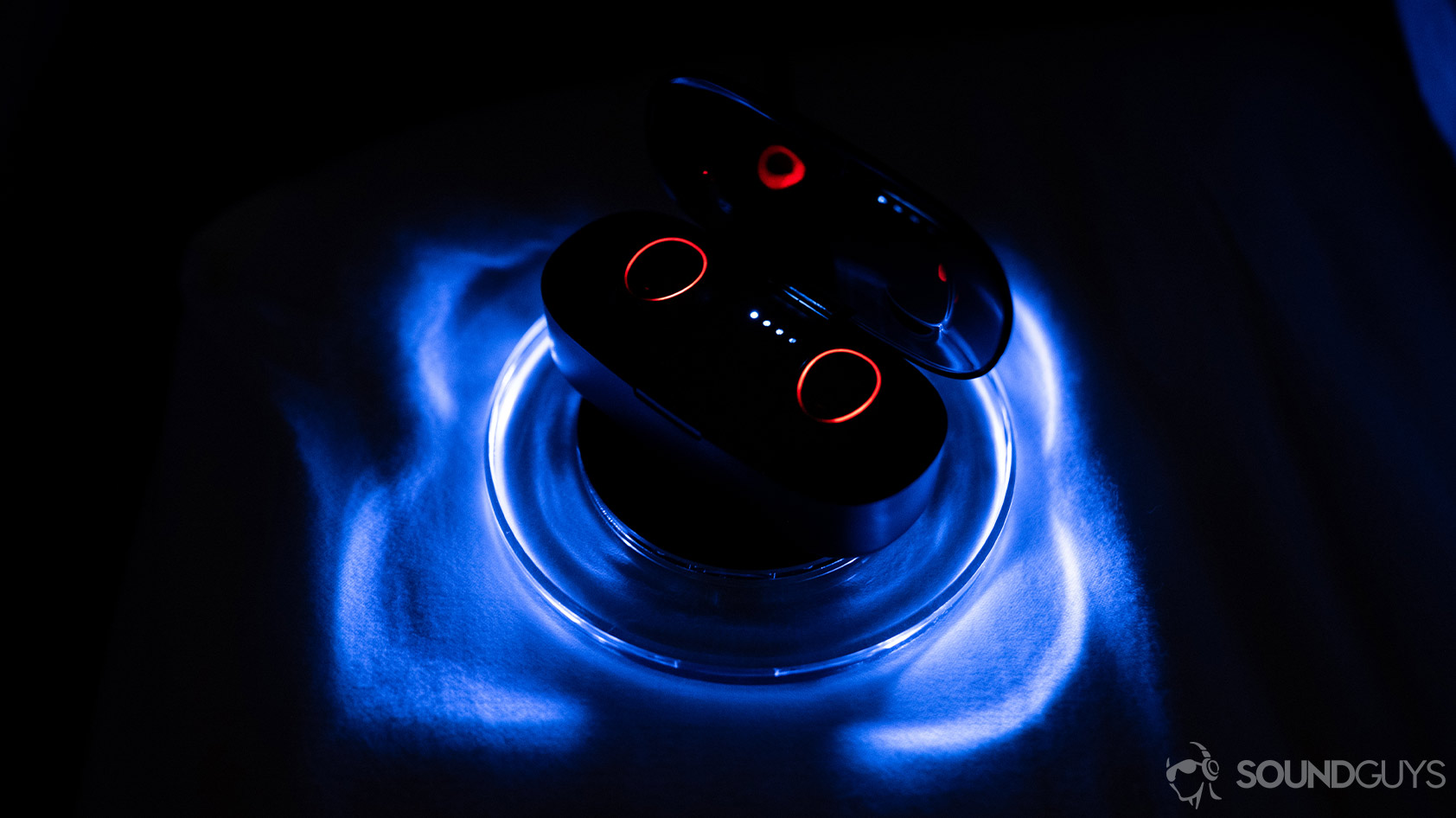 A picture of the Klipsch S1 True Wireless earbuds in the charging case on the included wireless charging pad that glows blue when active.