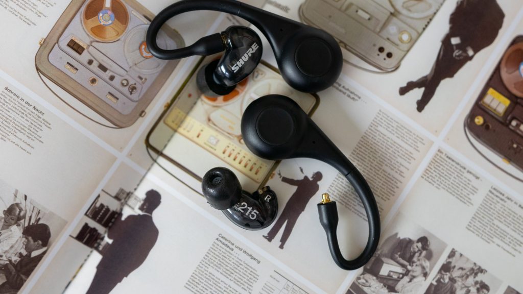 The Shure Aonic 215 disconnected from the adapters on top of a textbook illustration.