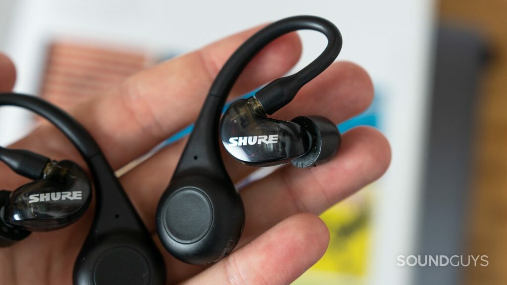 A man holds the Shure Aonic 215 true wireless earbuds and adapters.