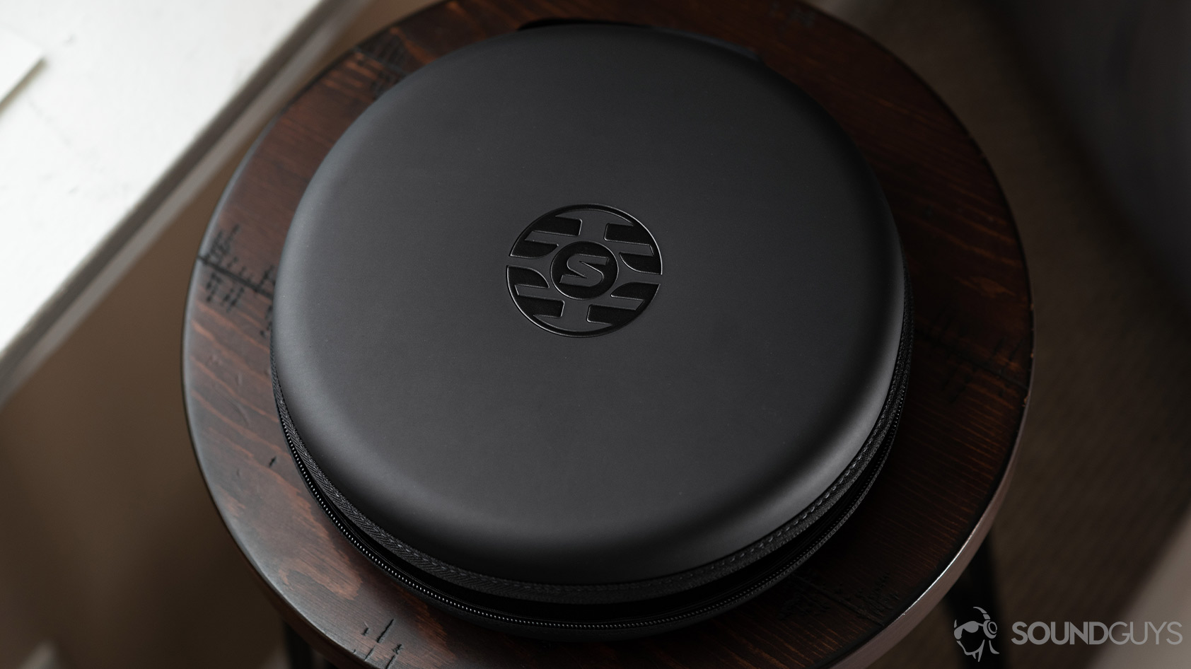 An aerial photo of the Shure Aonic 50-noise canceling headphones closed carrying case on a wooden bar stool.