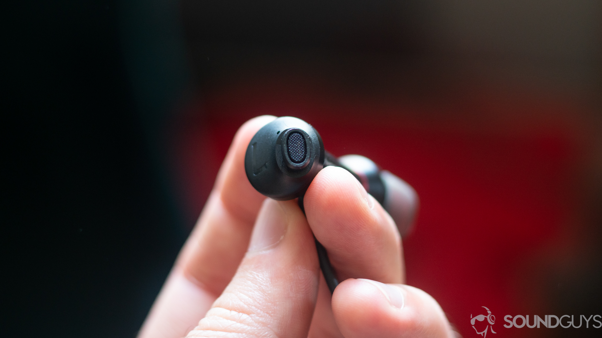 A picture of a man holding a single earbud of the 1More Dual Driver ANC Pro showing the oblong shape.