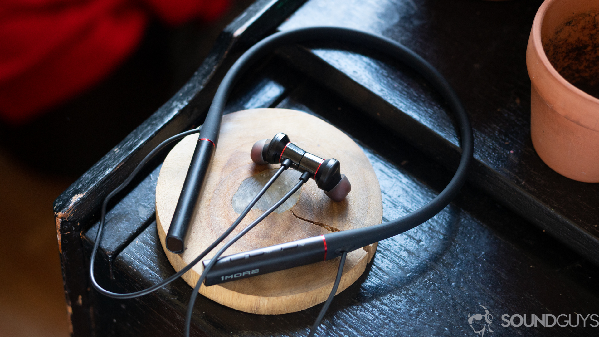 The 1More Dual Driver ANC Pro earbuds on a wooden coaster on top of black table