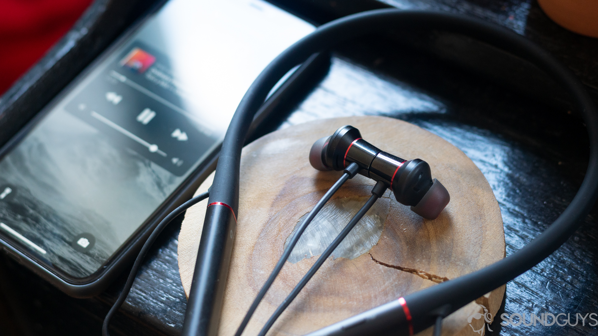 1More Dual Driver ANC Pro earbuds on table 1More Dual Driver ANC Pro on table next to iPhone 11 Pro with music playing on screen.