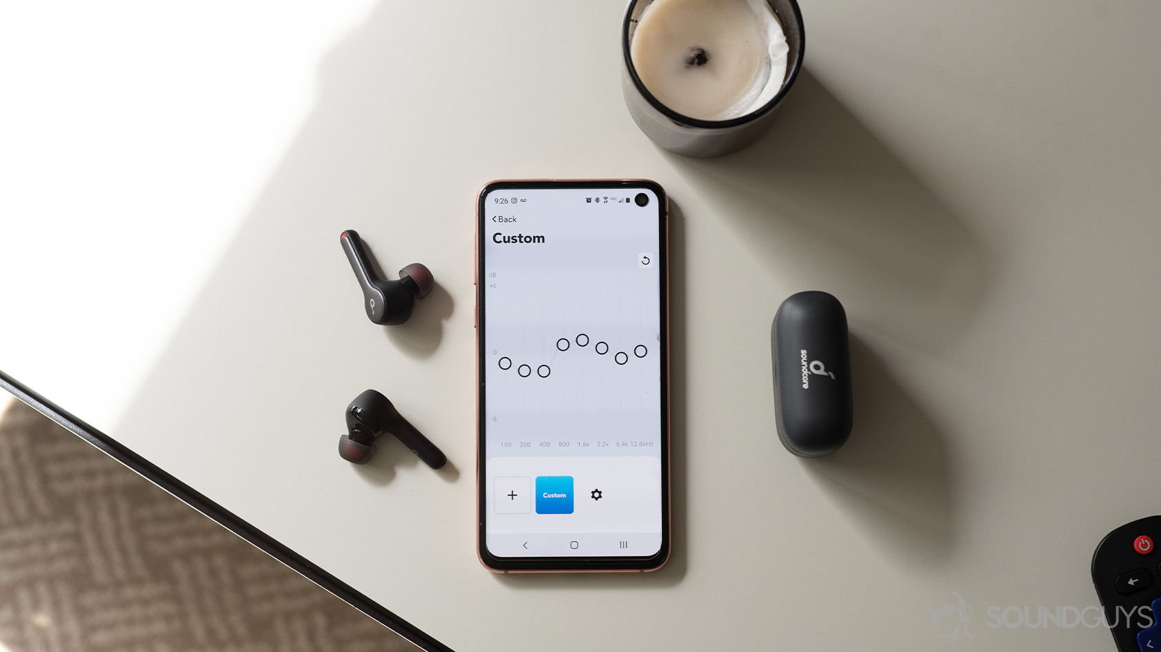 An aerial picture of the Anker SoundCore Liberty Air 2 true wireless earbuds next to a Samsung Galaxy S10e with the SoundCore mobile app equalizer open.