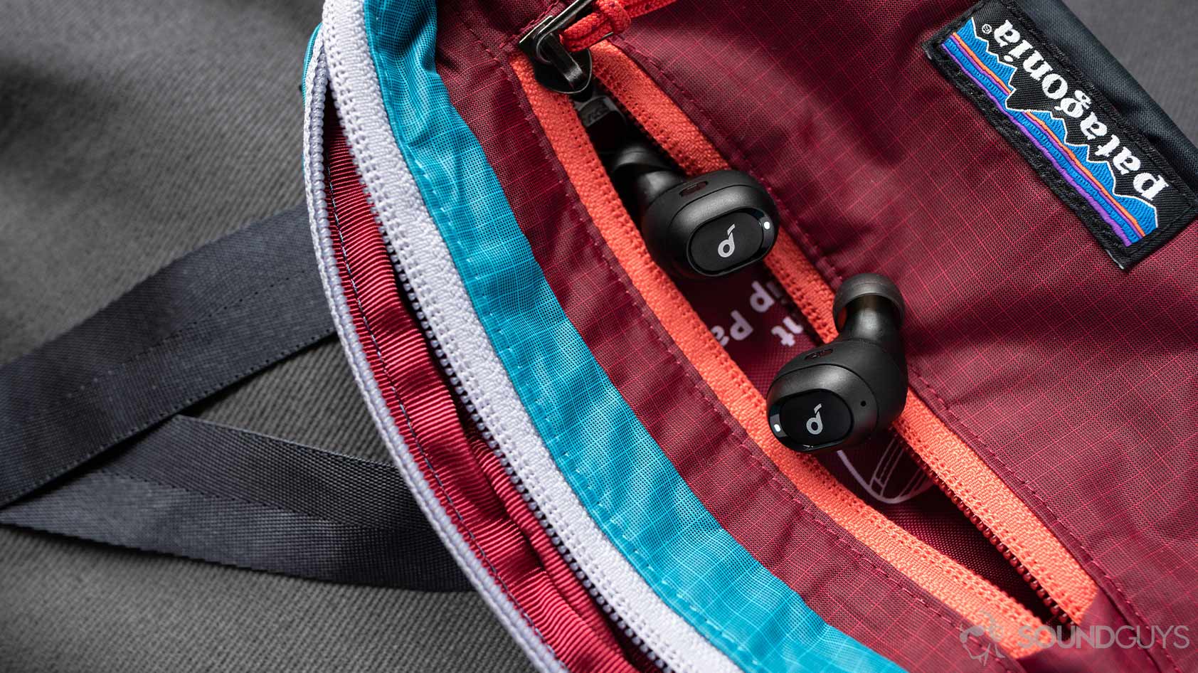 A picture of the Anker SoundCore Liberty Neo true wireless earbuds in a Patagonia fanny pack.