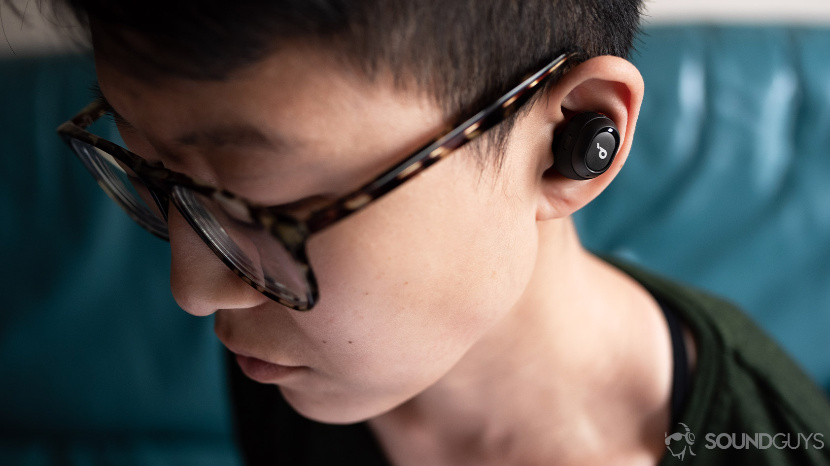 A picture of the Anker SoundCore Liberty Neo true wireless earbuds worn by a woman looking down.