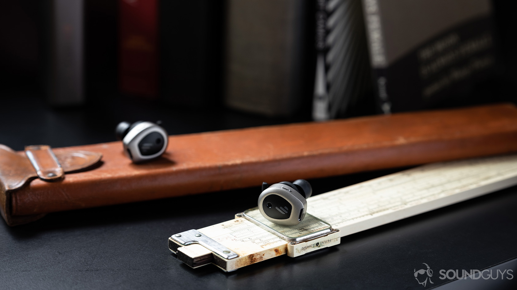 A picture of the Edifier TWS NB true wireless noise canceling earbuds on a leather rectangle and measuring stick.