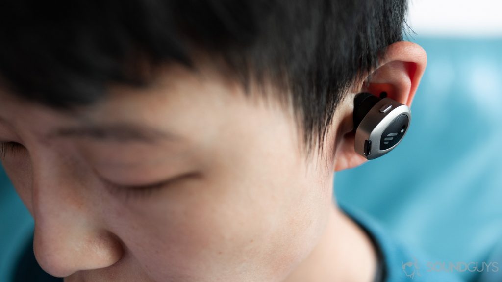 A picture of the Edifier TWS NB true wireless noise canceling earbuds worn by a woman looking down to show how much they protrude from the ear.