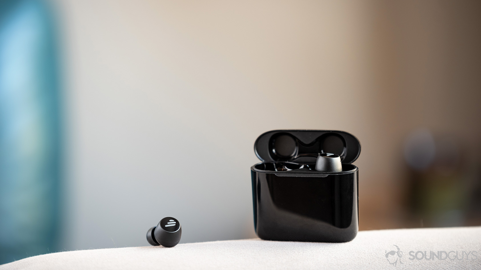 A picture of the Edifier TWS6, a more premium version of the TWS1, true wireless earbuds in black on a couch arm.