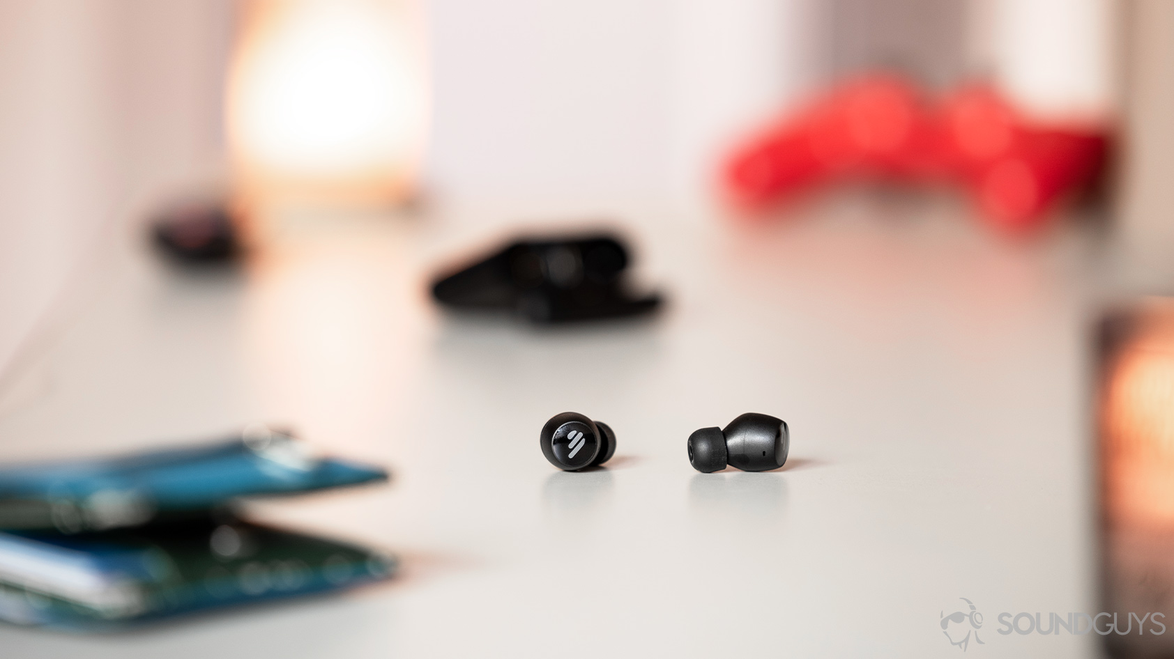 A picture of the Edifier TWS6 true wireless earbuds on a cream-colored coffee table with candles in the foreground and background.