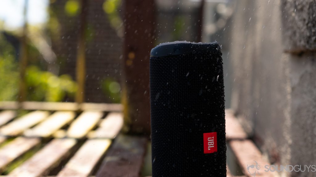 The JBL Flip 5 in black outside with water spraying onto it