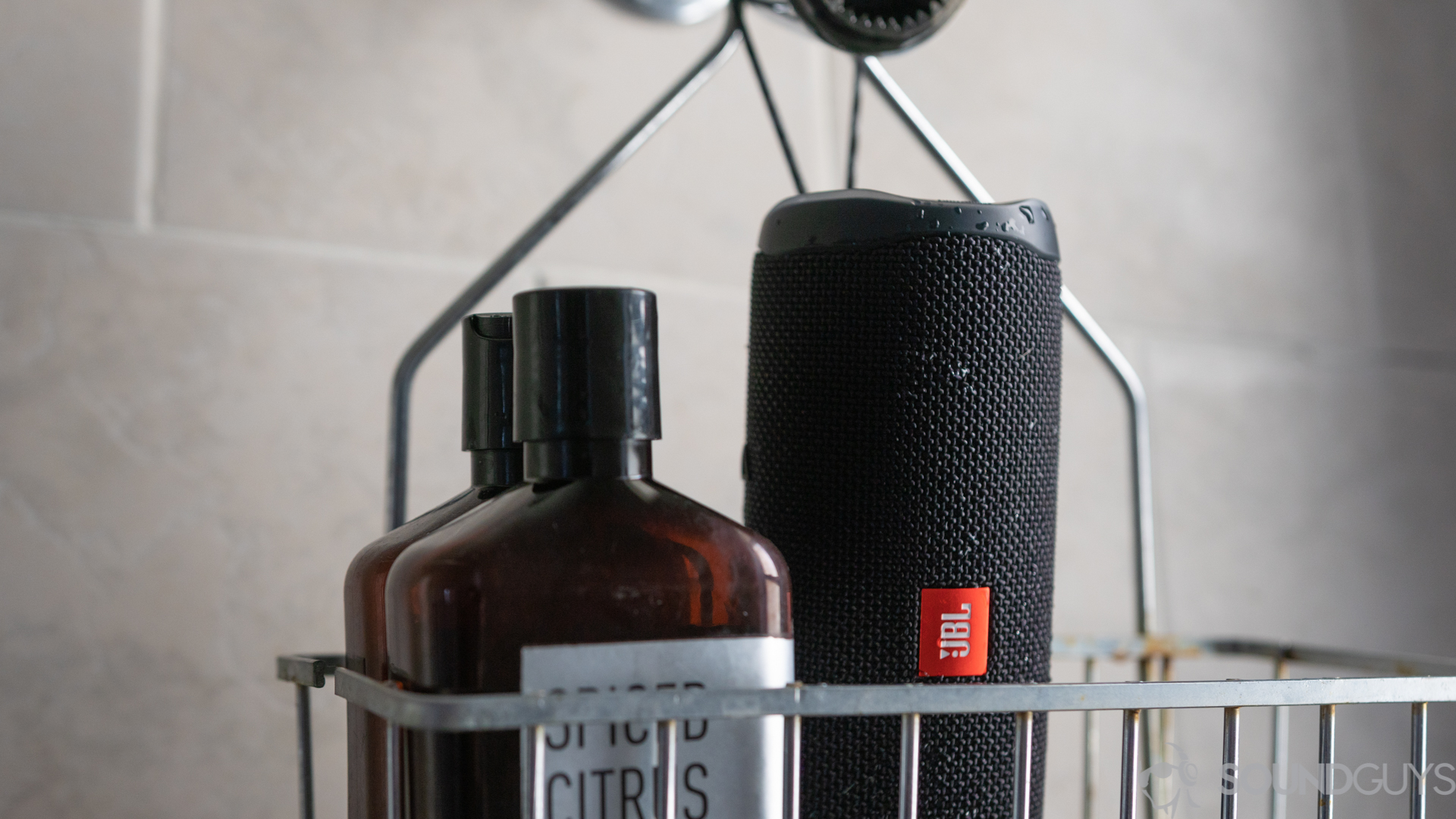 JBL Flip 5 hanging from showerhead next to shampoo