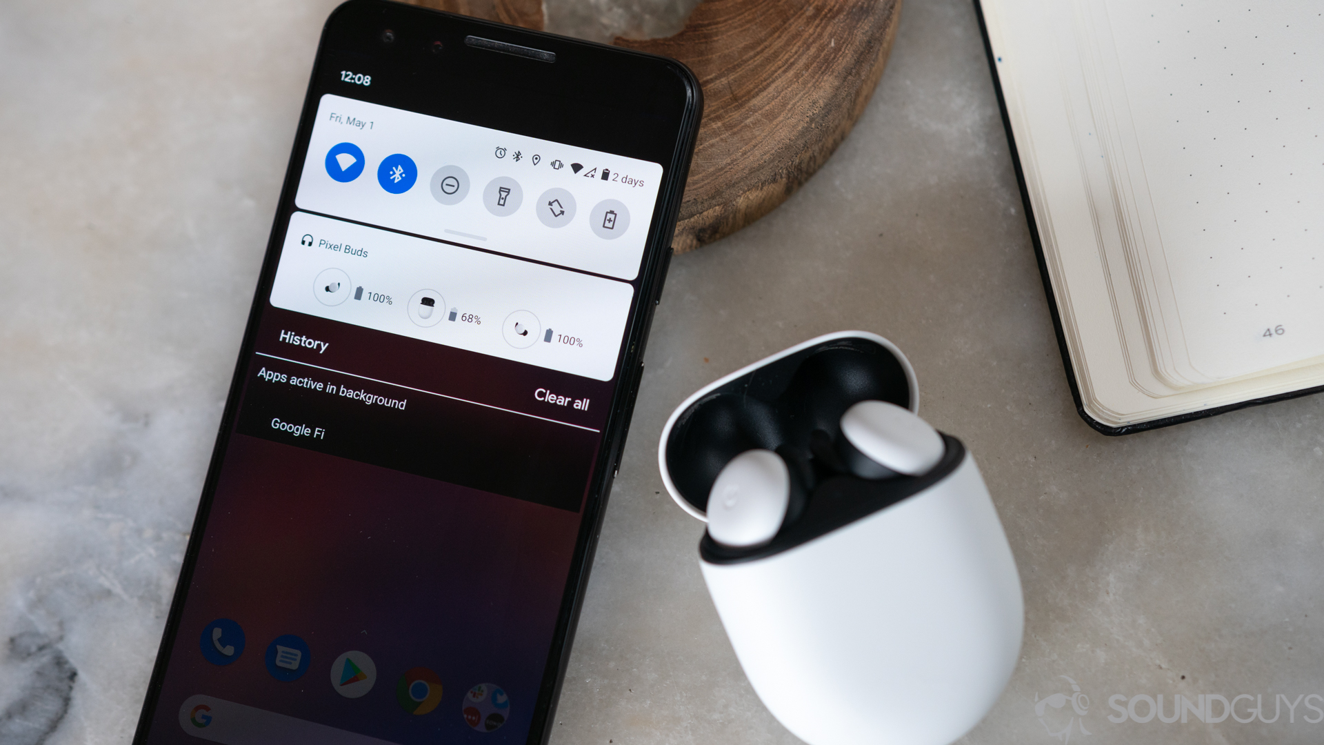 The new white Google Pixel Buds on a marble table next to Pixel 3 with battery card displayed