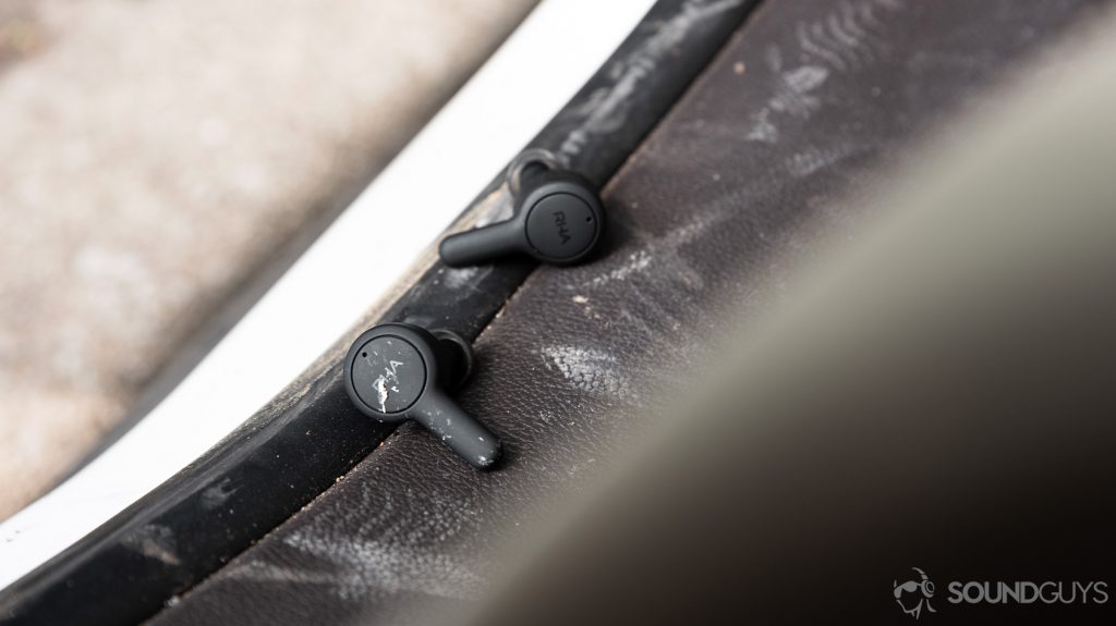 RHA TrueConnect 2 true wireless earbuds on a dirty surface with dirt on the earbuds.