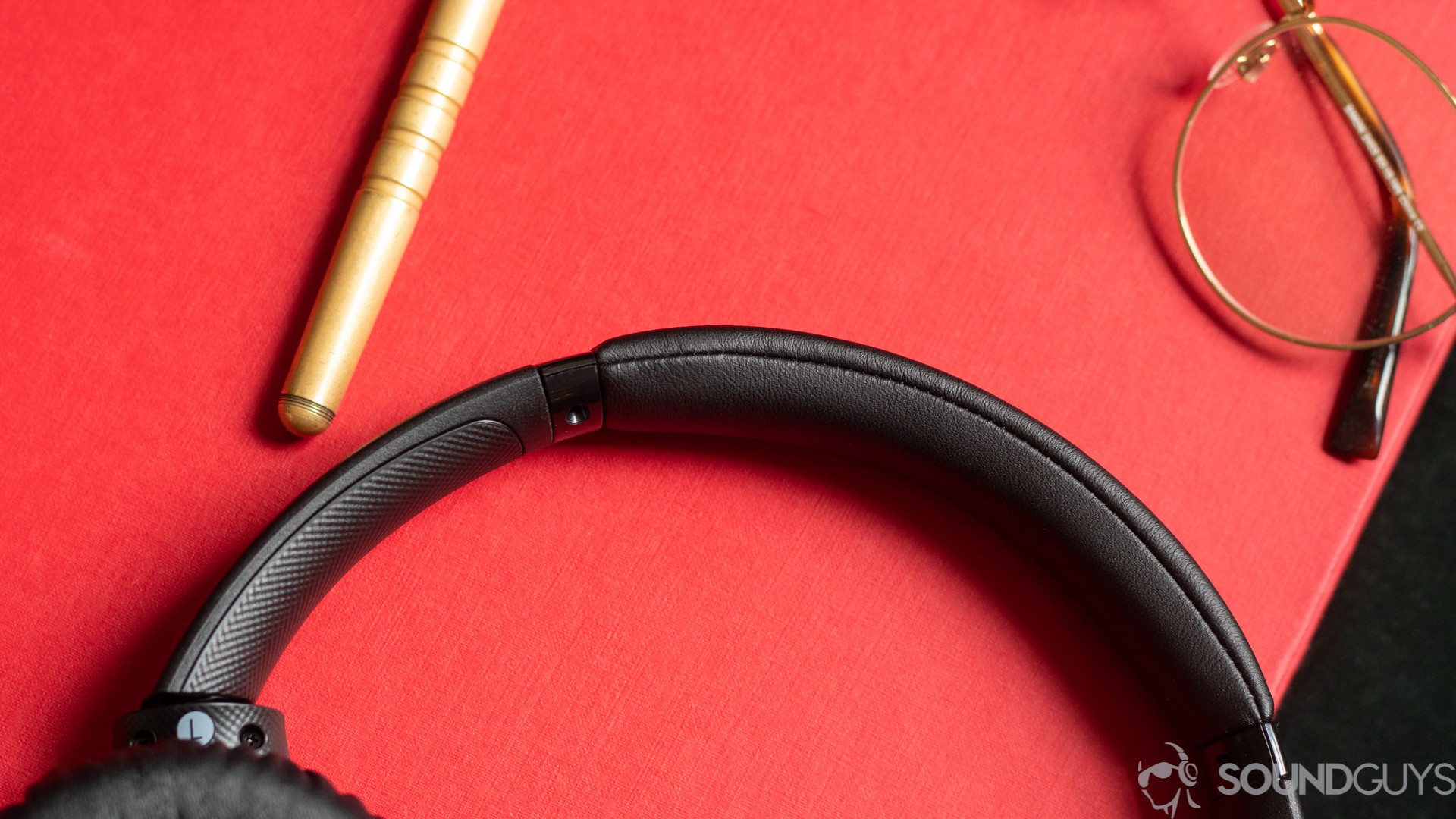 Close-up shot of the Sony WH-CH710N headband padding pictured on top of red book next to gold glasses and brass pen.