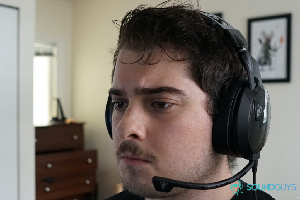 A man sits at a PC wearing The Turtle Beach Elite Atlas gaming headset.