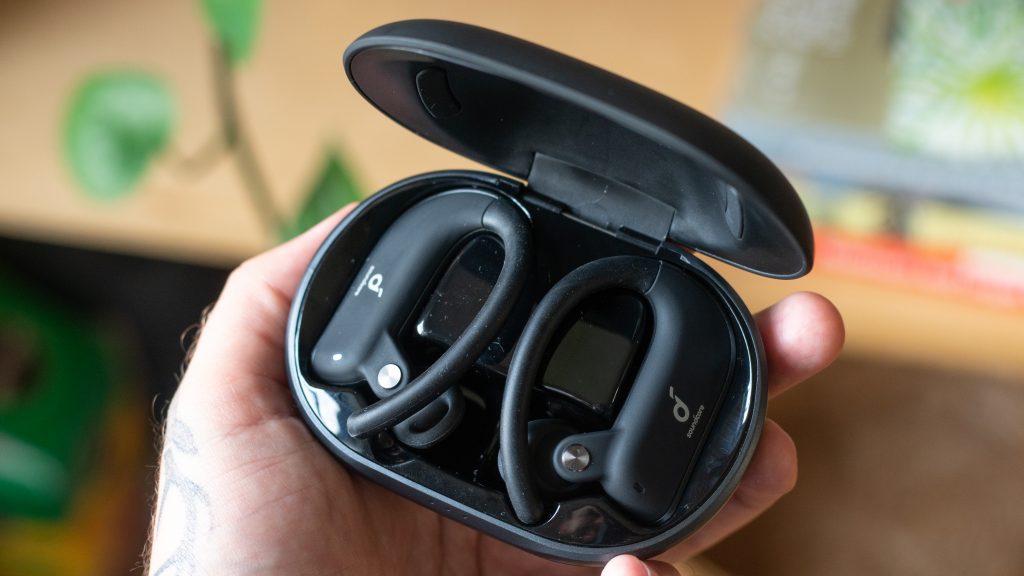 Man holding Anker Soundcore Spirit X2 with lid open and earbuds visible.