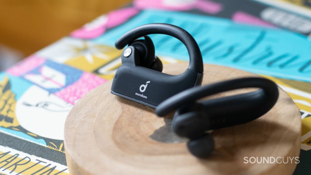 Anker Soundcore Spirit X2 earbuds on a wooden coaster on top of a colorful book cover