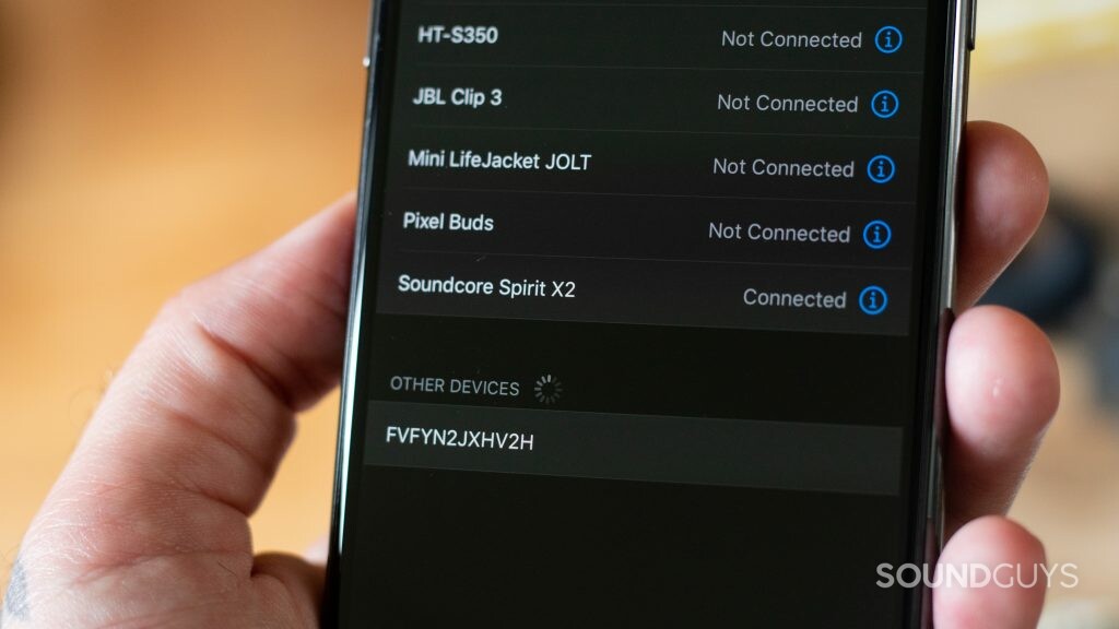 Shot of man holding iPhone 11 Pro withnker Soundcore Spirit X2 being connected in the Bluetooth settings