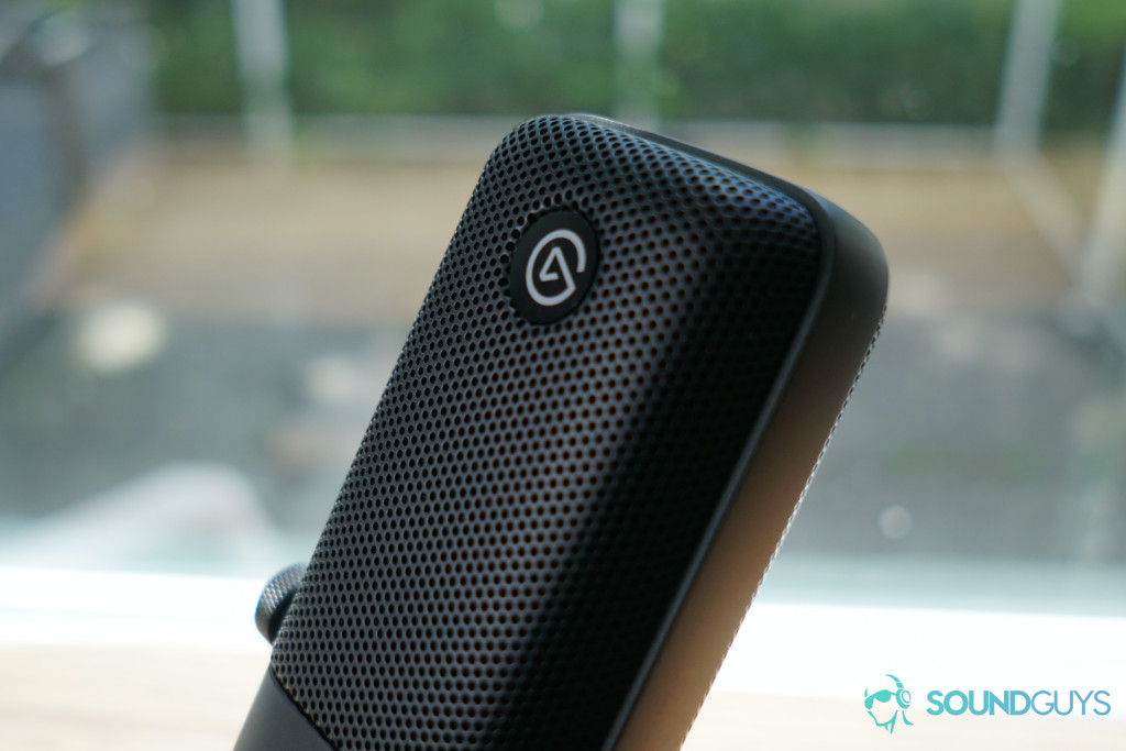 A detail shot of the Elgato logo on the Elgato Wave:3 microphone which is sitting on a table by a window.