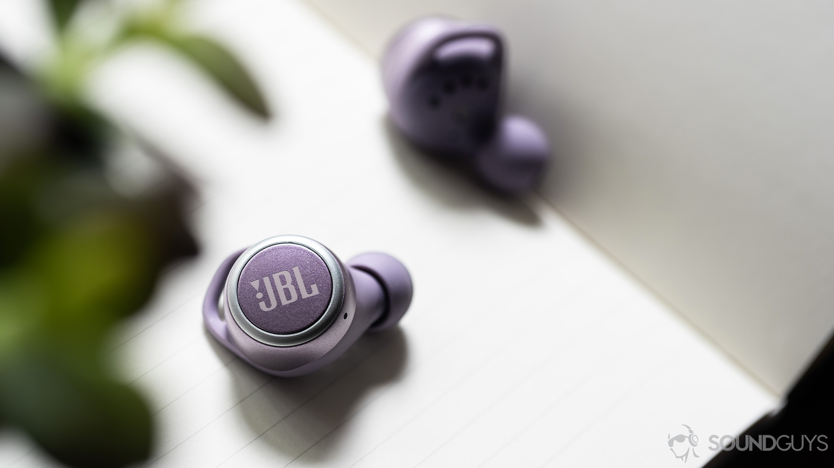 The JBL LIVE 300 TWS true wireless earbuds on a notebook.