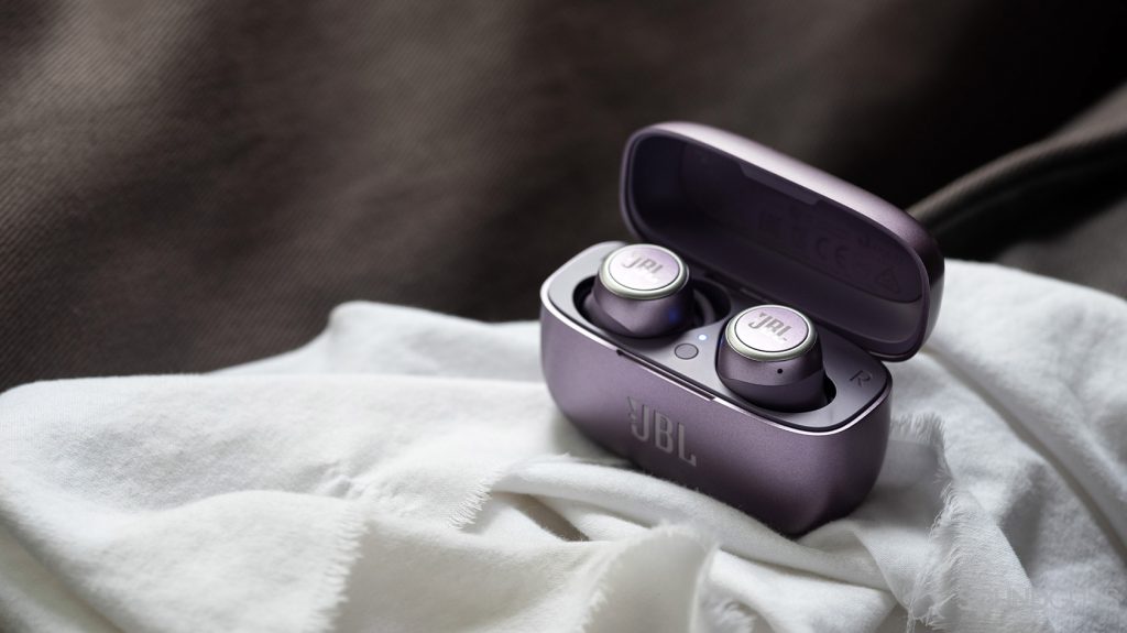 A picture of the JBL LIVE 300 TWS true wireless earbuds in the open charging case on top of a white cloth surface.